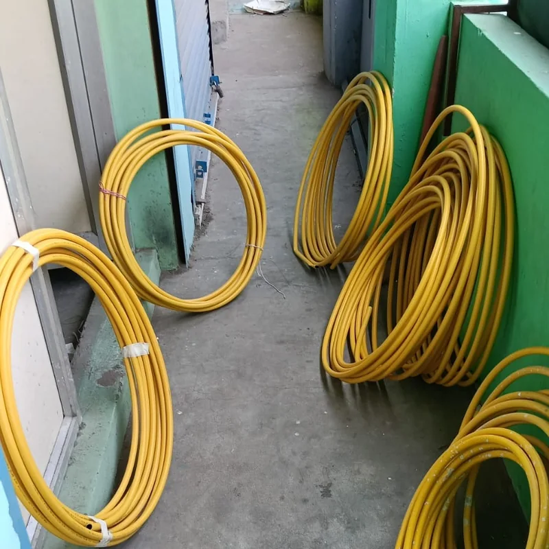 Coils of yellow composite gas pipe stacked at a job site, ready for installation