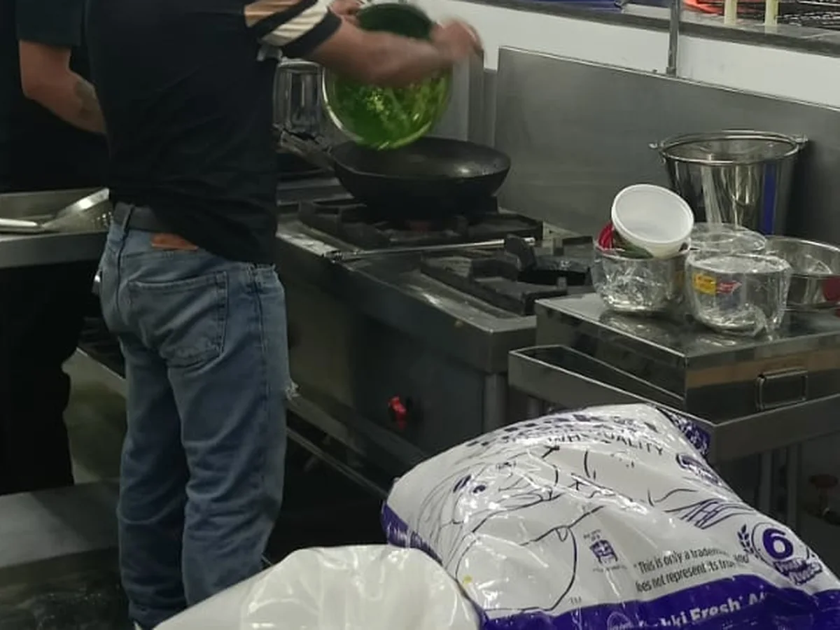 Commercial kitchen gas range in active use, connected to the pipeline in a high-volume kitchen
