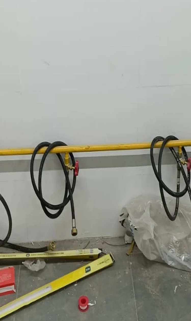 Restaurant gas pipeline manifold with coiled hoses and control valves along a kitchen wall